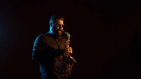 Handsome man playing the saxophone, black background, isolated, solo Stock Footage 127054399