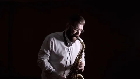 Handsome man playing the saxophone, black background, isolated, solo Video stock 127054576