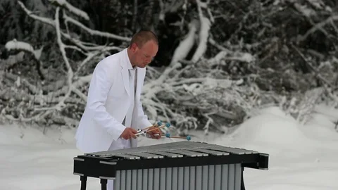 Handsome Man playing the vibraphone in snow with white suit Stock Footage 104460246