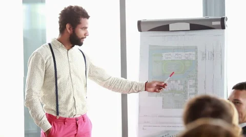 Handsome man pointing at flipchart while giving presentation to his colleagues Stock Footage 59542175