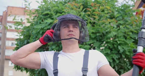 Handsome man posing at garden with electric trimming machine in hands. Stock Footage 194494865