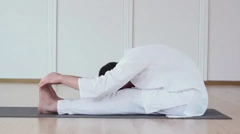 Handsome Man Practicing Yoga in a Studio. Paschimottanasana. Stock Footage 59729774