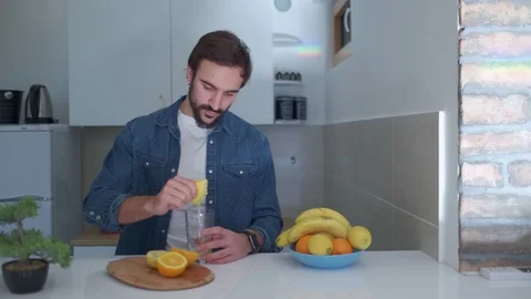 Handsome man preparing fresh fruit juice in the kitchen Stock Footage 127648944
