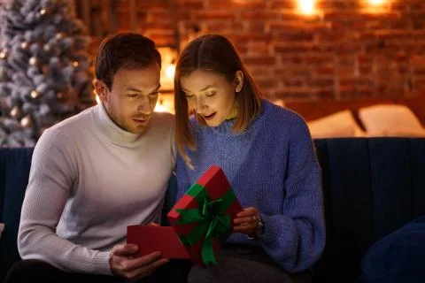 Handsome man presenting a gift to his beautiful wife and smiling. Beautiful 스톡 사진