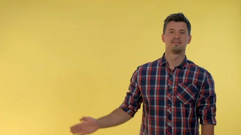 Handsome man presenting something on empty hand with yellow background. Stock Footage 120127845