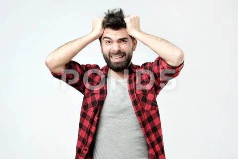 Handsome man pressing hands to head and clenching teeth panicking being in Stock Photos