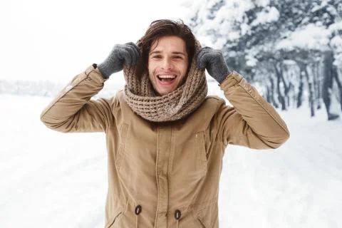 Handsome Man Pulling Scarf On Head Standing In Snowy Forest Stock Photos