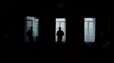 A handsome man puts on a jacket in front of a window Stock Footage 60592525