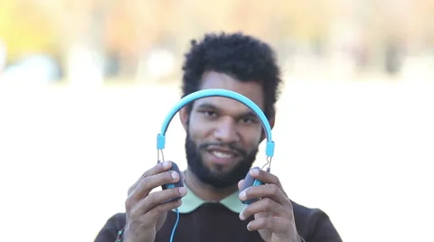 Handsome man putting on headphones and listening to music Stock Footage 59555296