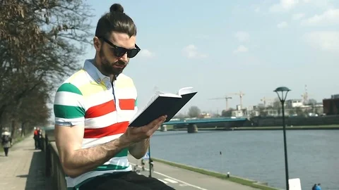 Handsome man reading book on boulevards and smiling to the camera Stock-Footage 74420319