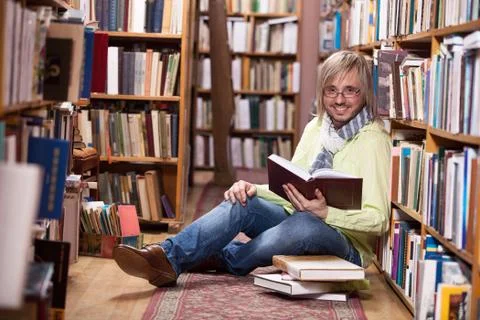 Handsome man reading book while sitting on floor Stock Photos