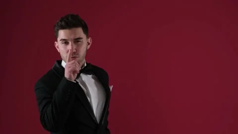 Handsome man on a red background adjusts his suit and flirts Stock Footage 169095633