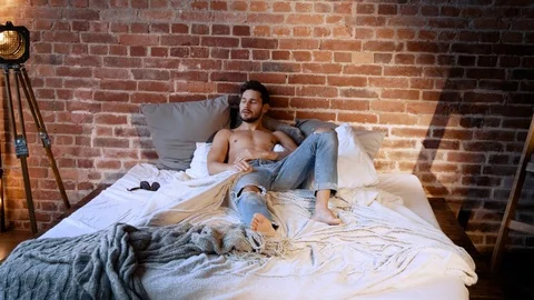 Handsome man relaxing on a bed Stock Footage 105199110