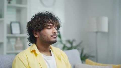 Handsome man relaxing at home closes his eyes and takes a deep breath of fresh  Stock Footage 235488948