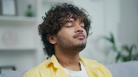 Handsome man relaxing at home closes his eyes and takes a deep breath of fresh  Stock Footage 235488993