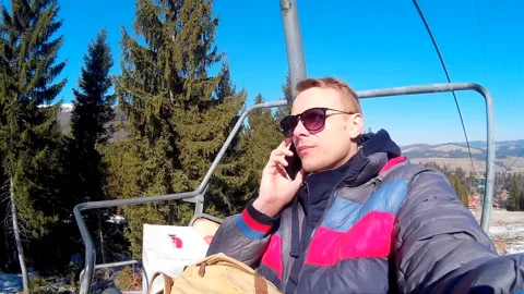 Handsome man rides a cable car against the background of a winter forest and Stock Footage 146483974