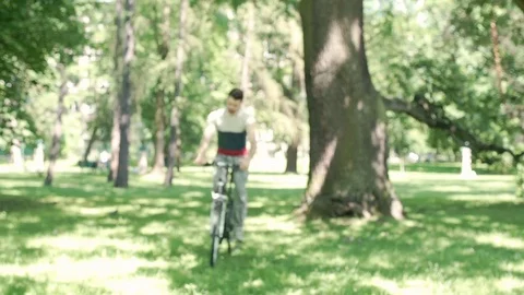Handsome man riding on his bicycle in the park, steadycam shot Stock Footage