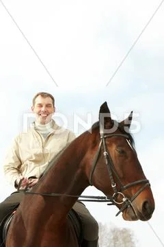 A handsome man riding a horse outside Stock Photos