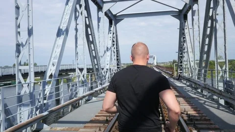 Handsome man is running across a old bridge in the city Video stock 84004312