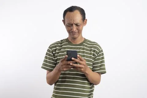 A handsome man sad while holding a smartphone in a studio setting with neut.. 库存照片