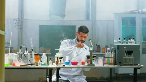 Handsome man scientist using a dropper to add into the glass tube he Stock Footage 153083263