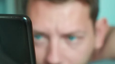 Handsome man scrolling smartphone in bed in the morning surfing internet Stock Footage 250116969
