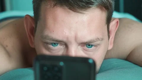 Handsome man scrolling smartphone in bed in the morning surfing internet Stock Footage 250117036