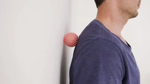 Handsome man shows exercises using wall and the mini fitness ball Video stock 297222035