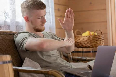 Handsome man shows gestures when communicating on social networks using laptop Foto stock