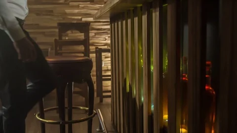 Handsome man sits down at a counter bar and orders a drink Stock Footage 112191722