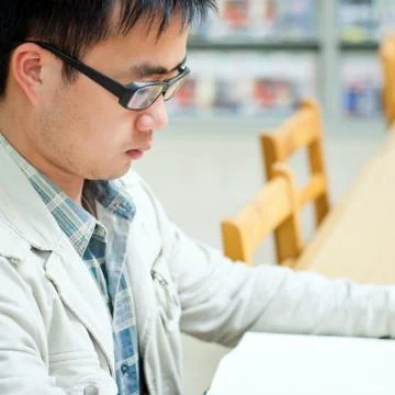 Handsome man sitting and reading in library Stock Photos