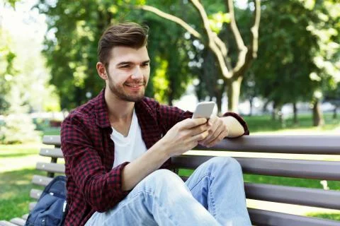 Handsome man sitting and using smartphone outdoors Foto stock