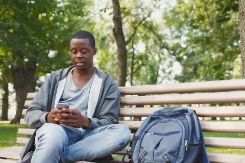 Handsome man sitting and using smartphone outdoors Foto stock