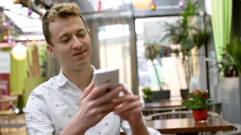 Handsome man sitting in the cafe and doing selfies on smartphone, steadycam shot Stock-Footage 71865795