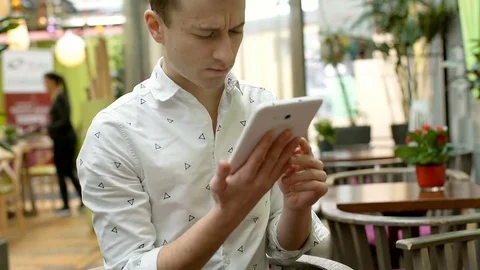 Handsome man sitting in the cafe and browsing internet on tablet, steadycam shot 스톡 동영상 71872294