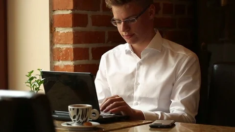 Handsome man sitting in the cafe and working on laptop Stock Footage 80423795