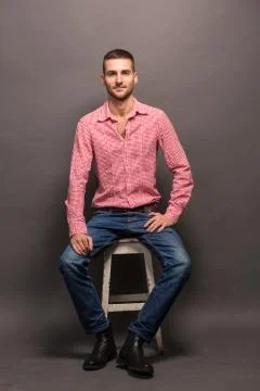 Handsome man sitting on a chair in studio Stock Photos