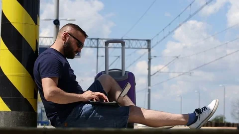 Handsome man sitting on the platform and typing on laptop Stock Footage 78650138