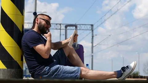 Handsome man sitting on the platform and browsing internet on tablet Stock Footage 78650386