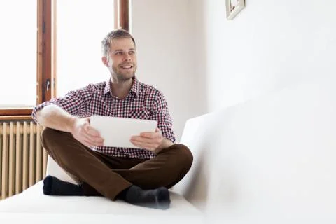 Handsome man sitting on sofa using a digital tablet Stock Photos