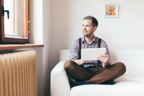 Handsome man sitting on sofa using a digital tablet Stock Photos