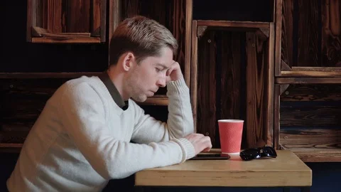 Handsome man sitting at the table and flipping smart phone Stock Footage 75650709