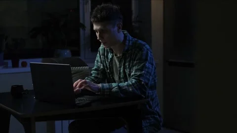 Handsome Man Sitting at a Table in a Cozy Kitchen and Using Laptop Computer at H Video stock 297188357