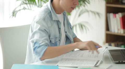 Handsome man sitting at table using laptop and writing in notebook Видео 27691948