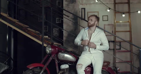 A handsome man sitting, then dancing on a old motorcycle Stock Footage 135114255