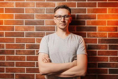 Handsome man smiling and posing against a red brick wall background. Lifestyl Stock Photos