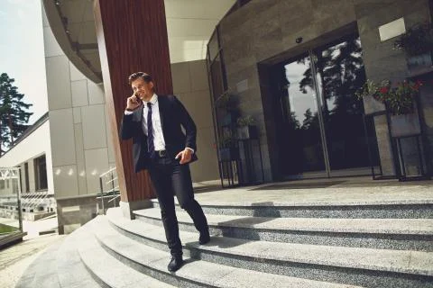Handsome man smiling and walking on the stairs with mobile phone Stock Photos