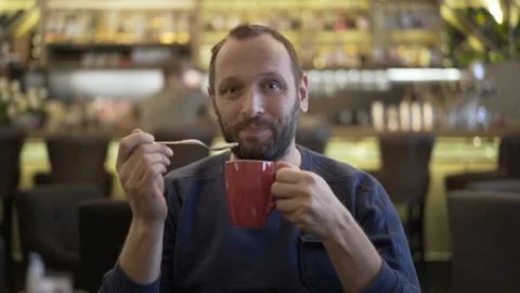 Handsome man smiling to the camera in the cafe and drinking cappuccino Stock Footage 87542430