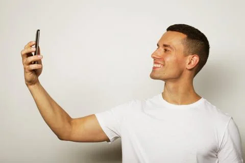 Handsome man smiling on camera taking selfie Stock-Fotos