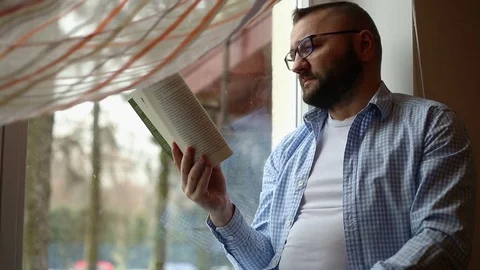 Handsome man smiling to the camera while reading book Stock Footage 71658443